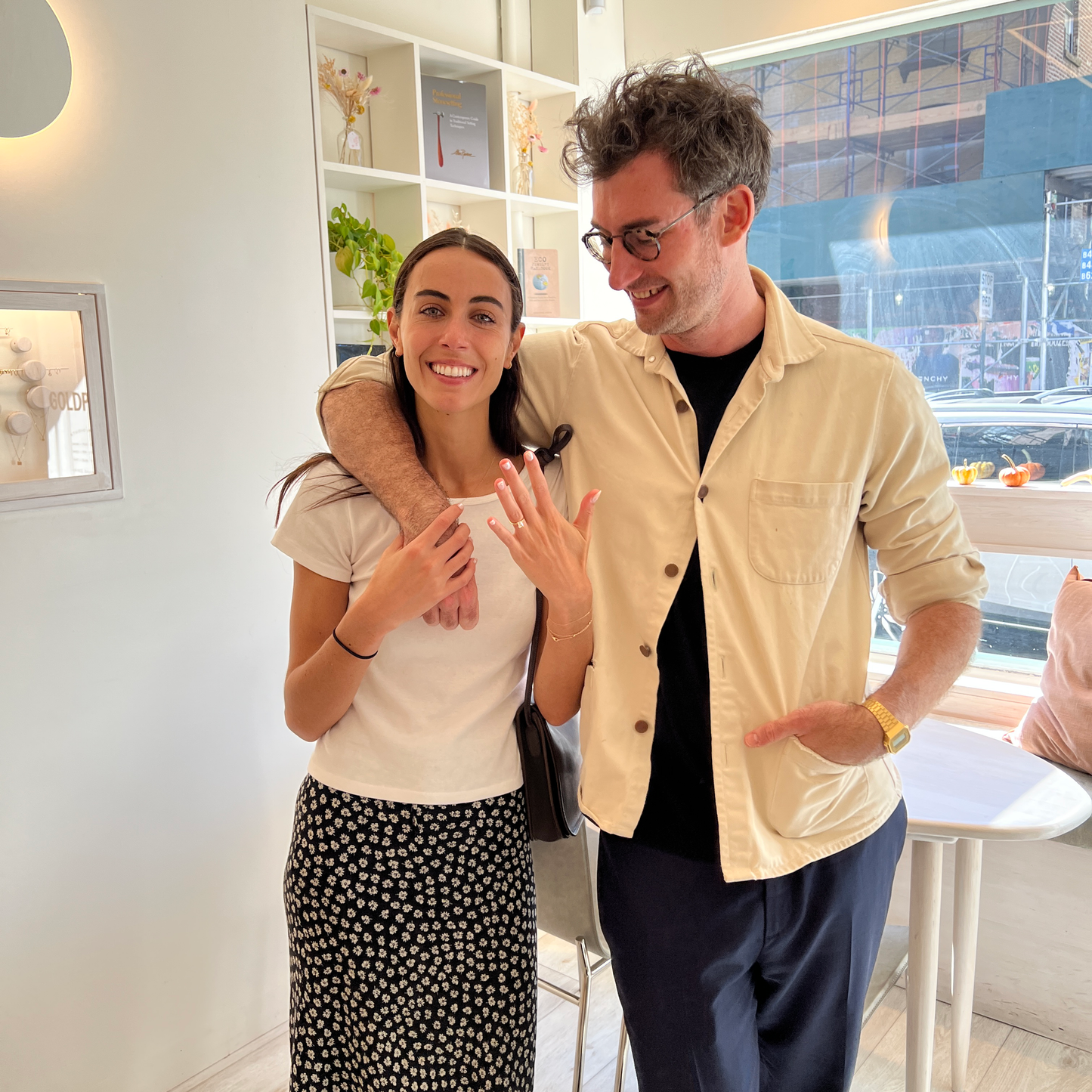 Kat and Tom embracing each other in our studio while lifts her hand to show her new engagement ring.