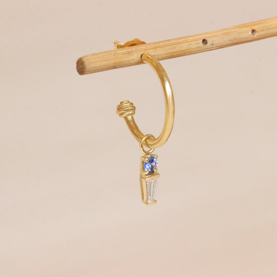 Angled lifestyle shot of Zigg Charm / Sapphire & Diamond on a Cornice collection hoop earring