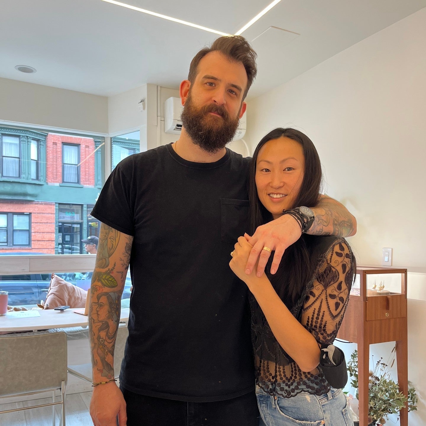 Jenna and josh holding eachother in our showroom while showcasing their new engagement rings.