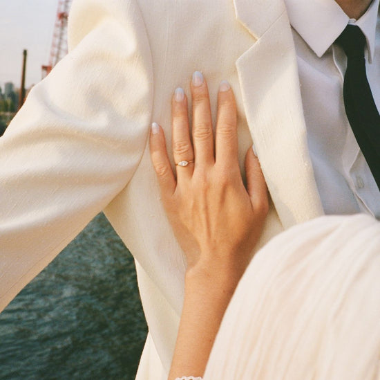 Maja's hand placed on Michael's white tuxedo jacket showcasing her new engagement ring on their wedding day.