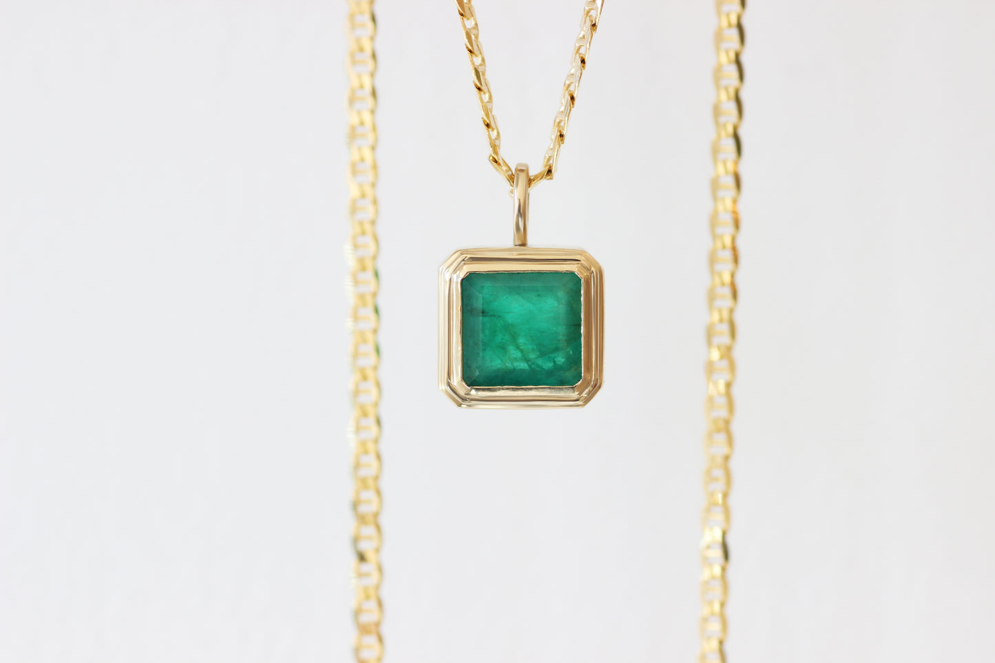 Custom pendant with client's own emerald cut emerald soft step bezel set in client's own recycled gold