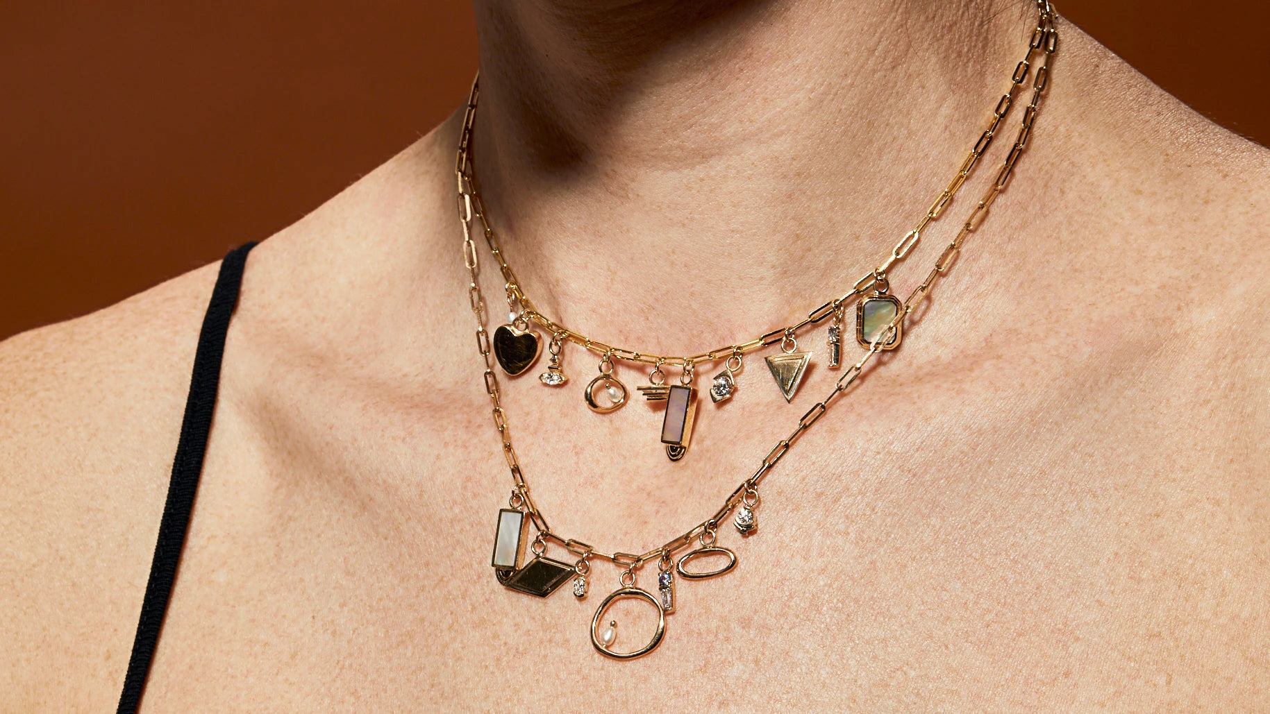 Model wears an array of charms on two different chain necklaces all by Goldpoint