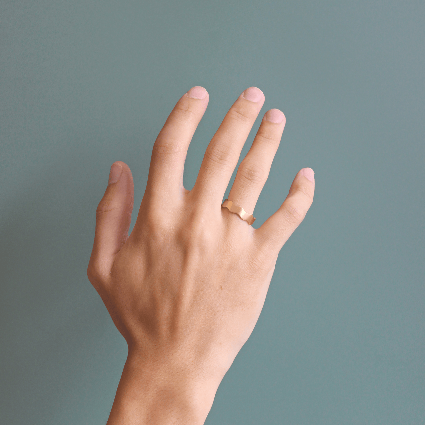 Model wears Waves Band / Wide in 18k yellow gold on ring finger by Goldpoint