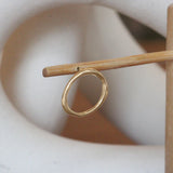 Lifestyle front view of Amorphous Earring / Large Circle on a wooden stand with a blurred background