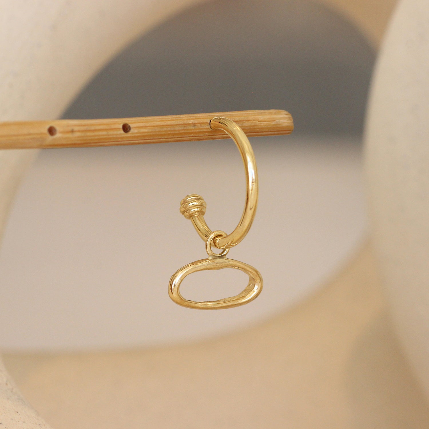 Lifestyle angle view of Amorphous Charm / Oval Sideways on a Cornice Hoop by Goldpoint Jewelry 