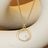Lifestyle front view of Amorphous Pearl Bead Charm / Large Circle by Goldpoint Jewelry on a chain over a ceramic