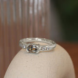 Lifestyle angled view of Ash Ring Oval Sapphire 0.615ct by Goldpoint Jewelry sitting ona. ceramic with a blurred background