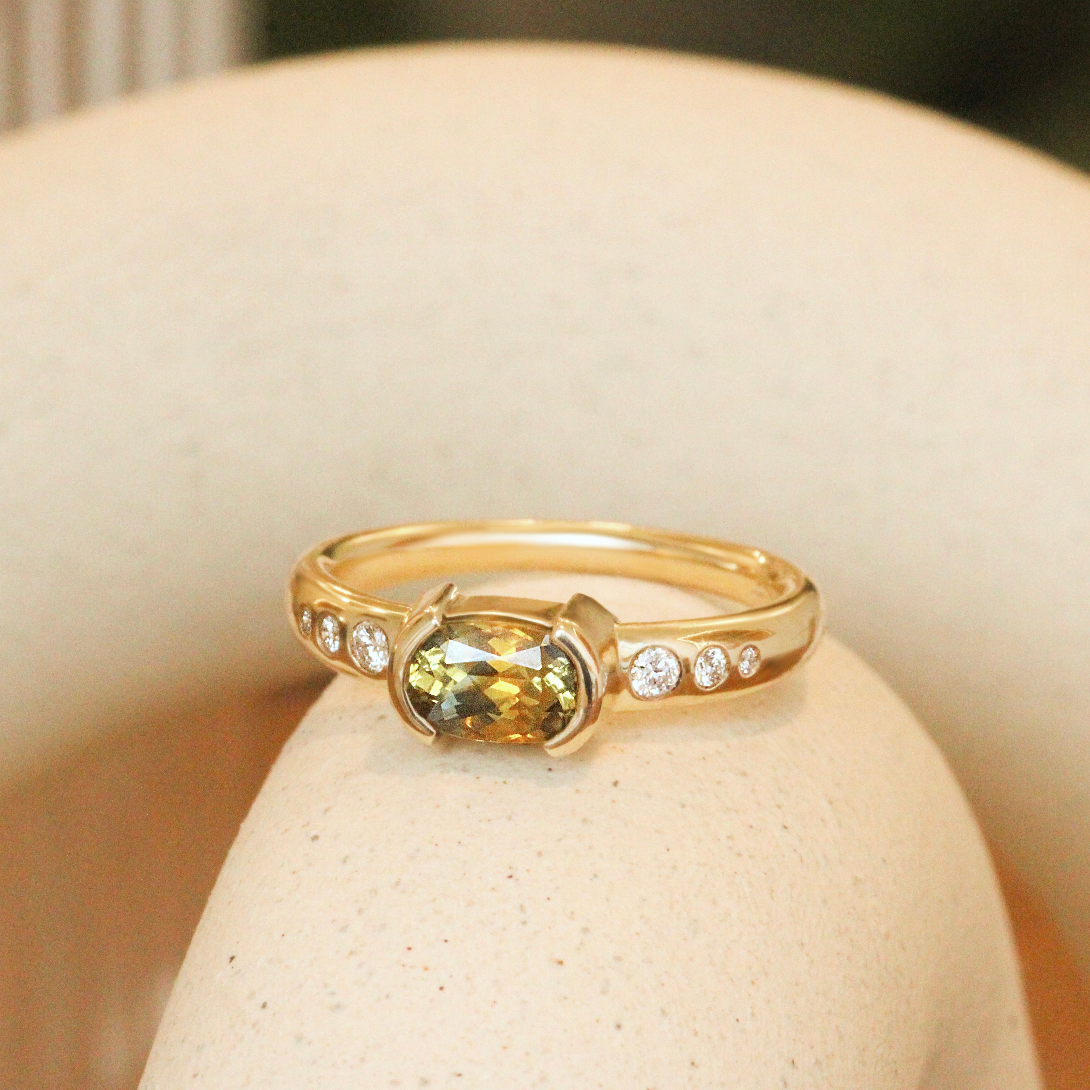 Lifestyleangled side view of Ash Ring Elongated Cushion Sapphire 1.04ct by Goldpoint Jewelry on a ceramic with blurred background