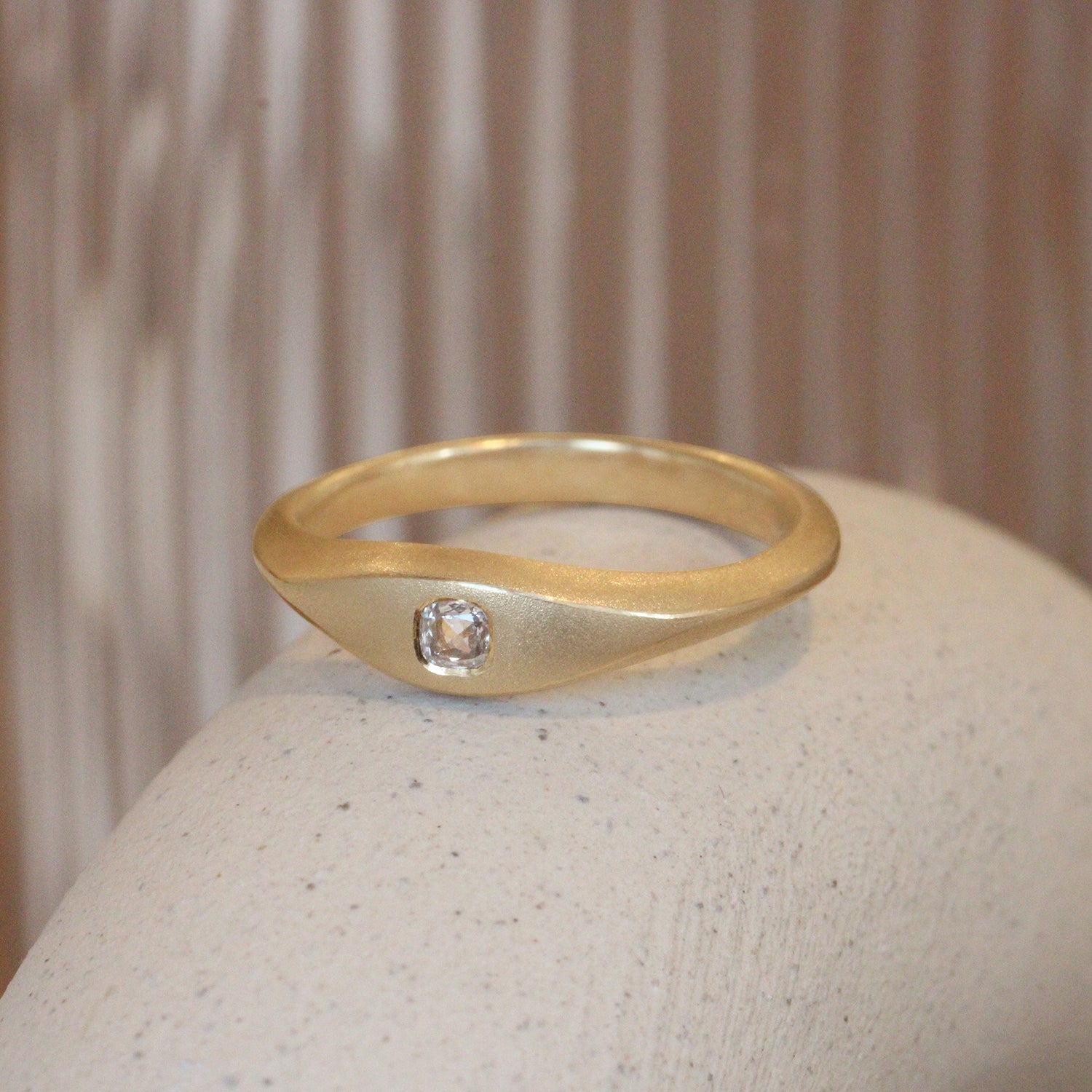 Lifestyle angled view of Astrid Ring / Cushion Natural Diamond 0.2ct by Pieces of Starr on a ceramic with taupe blurred background
