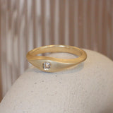 Lifestyle angled view of Astrid Ring / Cushion Natural Diamond 0.2ct by Pieces of Starr on a ceramic with taupe blurred background