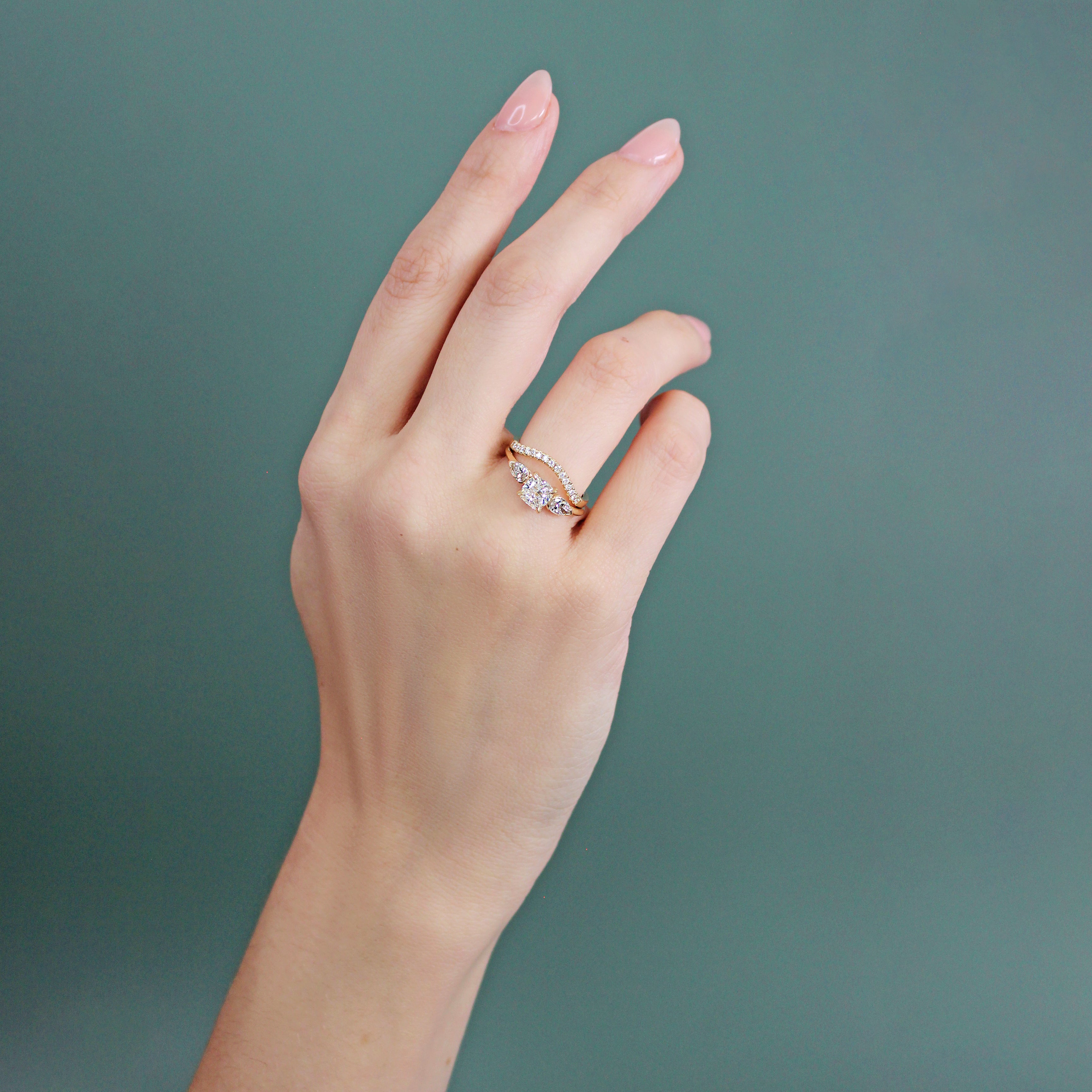 Model wears Flat Band Deep Curve Pave Round Lab Diamonds in 14k yellow gold stacked with an engagement ring