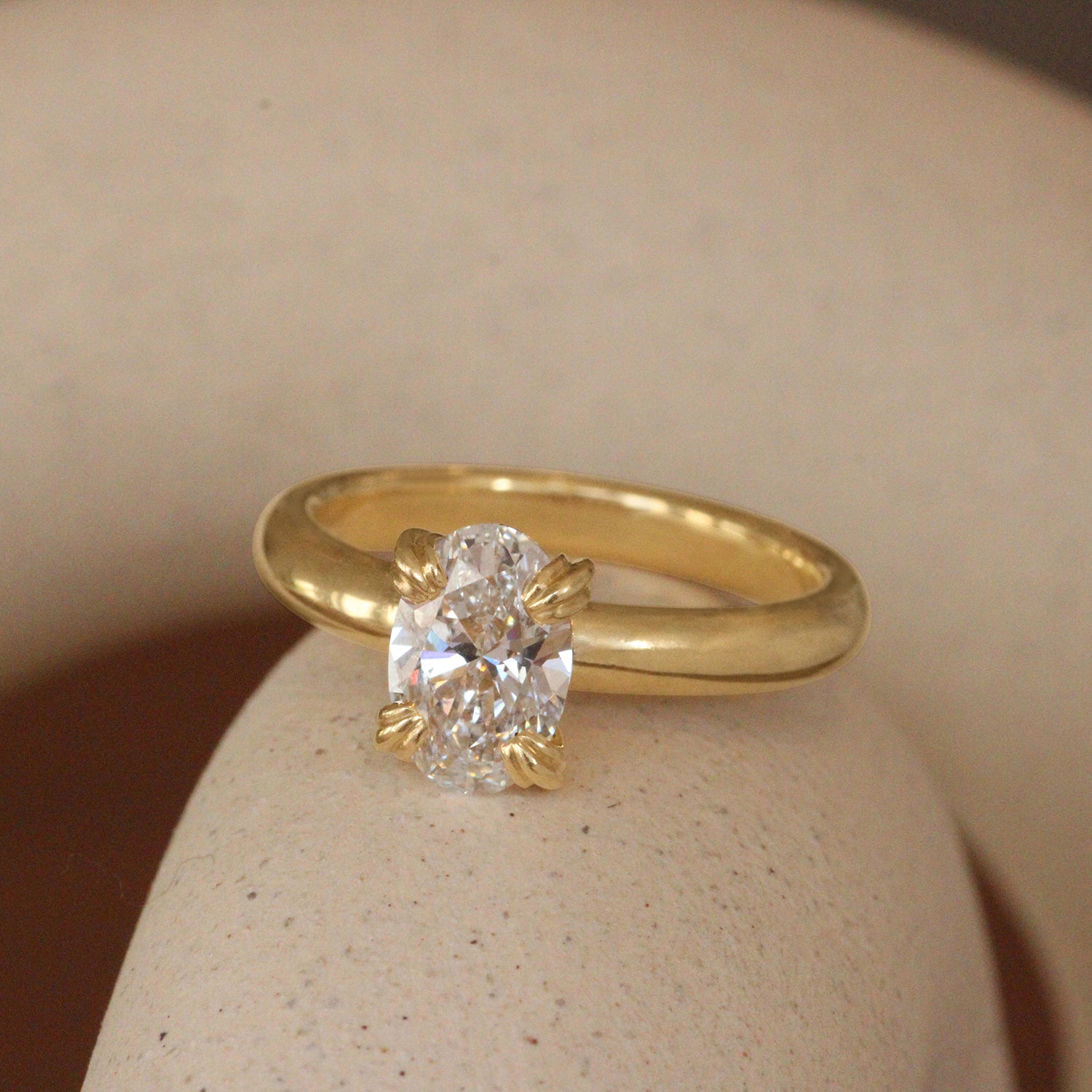 Lifestyle angled  view of Calyer Ring Oval Lab Diamond 1.56ct by Goldpoint Jewelry on a ceramic with a taupe blurred background