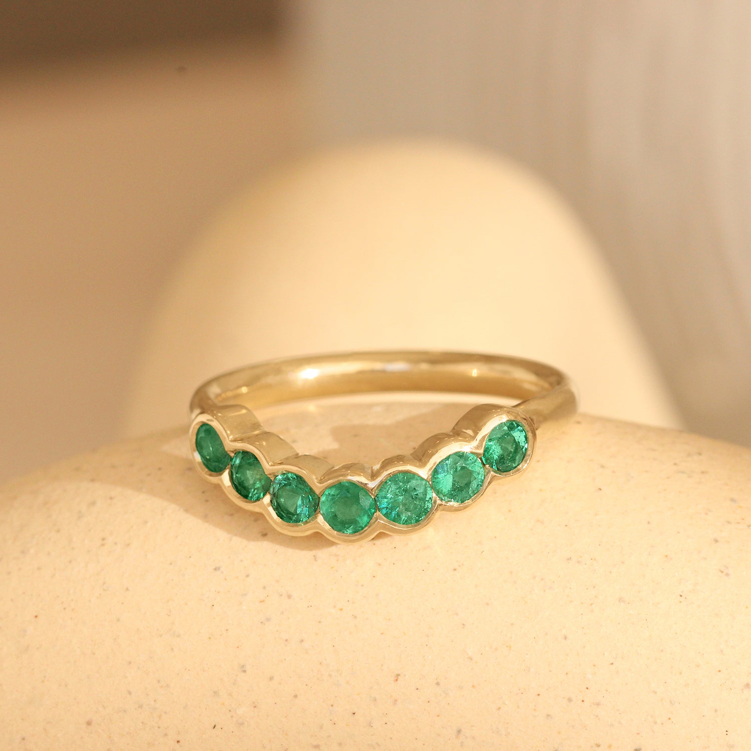 Lifestyle angled view of Cloud 7 Band Curve Round Emeralds in 14k yellow gold