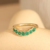Lifestyle angled view of Cloud 7 Band Curve Round Emeralds in 14k yellow gold