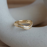 Lifestyle angled side view of Cornice Band Deep Curve / Pave Round Diamonds / in 14k Yellow Gold by Goldpoint Jewelry on a ceramic with blurred background