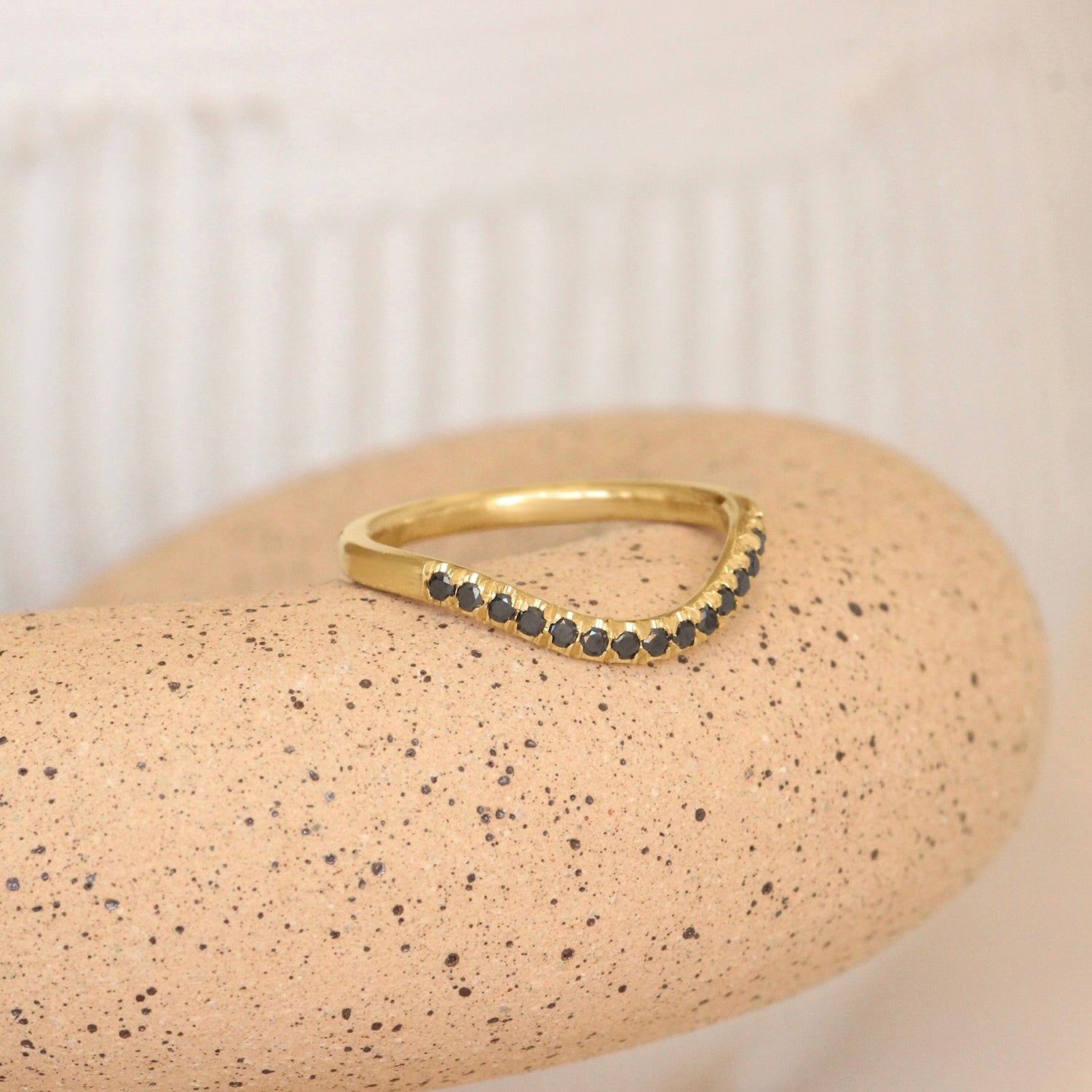 Lifestyle angled view of Flat Band Deep Curve Pave Round Black Diamonds in 14k yellow gold