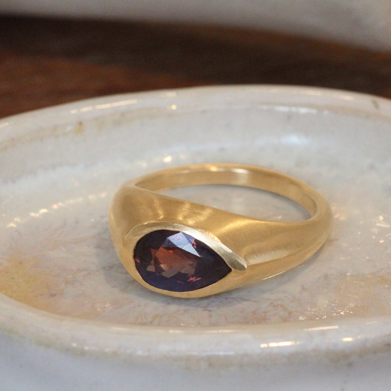 Lifestyle angled side view of Deep Purple Sapphire Signet Ring /  Pear Cut Sapphire 2.35ct by 12th House on a ceramic