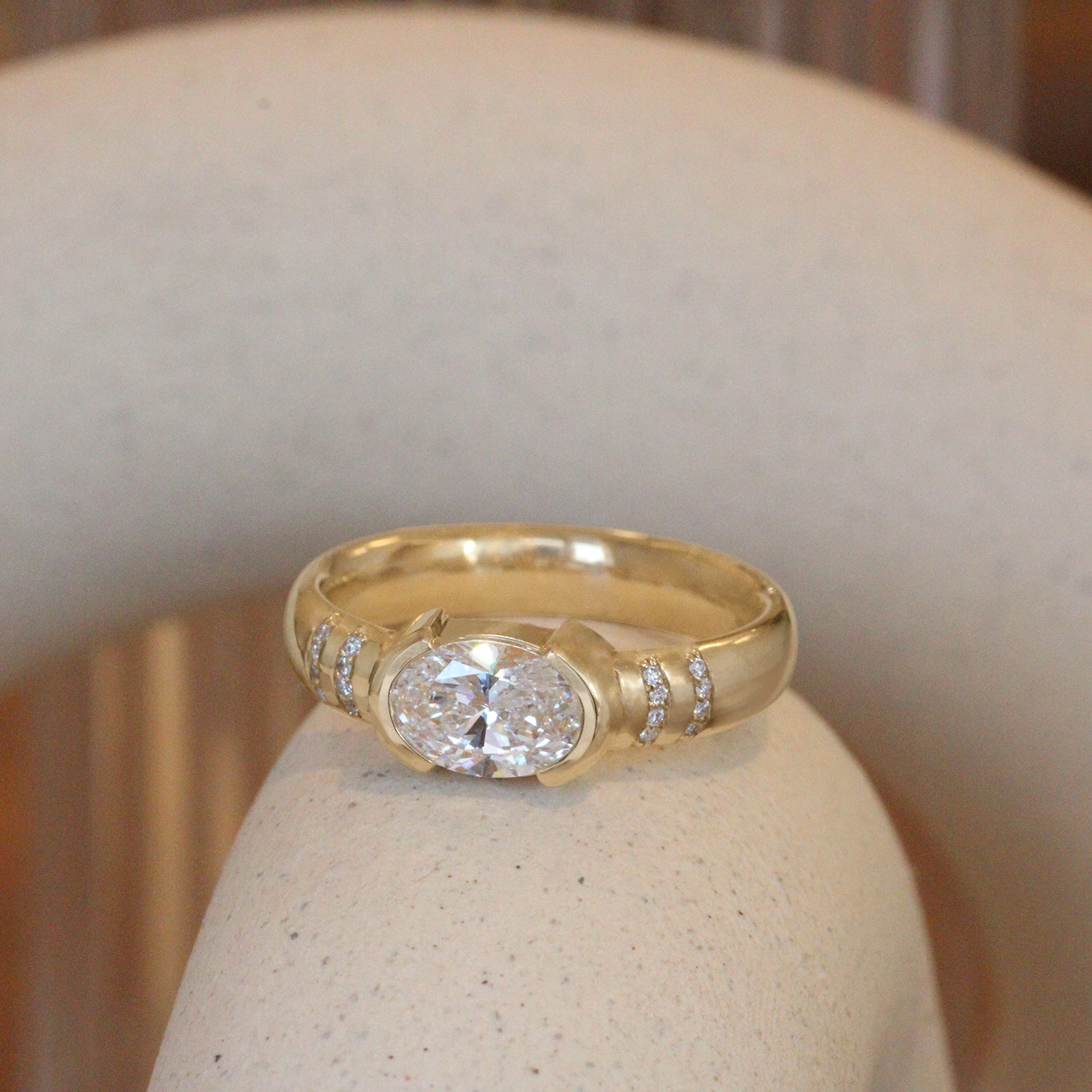 Lifestyle angled view of Dobbins Ring Oval Lab Diamond 1.01ct by Goldpoint Jewelry on a ceramic with a blurred background