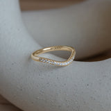 Lifestyle angled side view of Dome Band 2mm Deep Curve / Pave Round Lab Diamonds / in 14k Yellow Gold by Goldpoint Jewelry on a ceramic with blurred background