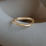 Lifestyle angled side view of Dome Band 2mm Soft Curve / in 14k Yellow Gold by Goldpoint Jewelry on a ceramic with blurred background