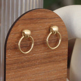 Lifestyle side angled view of Ruins Door Knocker Earring by Goldpoint Jewelry on a wood stand