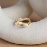 Lifestyle angled view of Duo Band Soft Curve / in Yellow Gold by Goldpoint Jewelry on a ceramic with a natural blurred backdrop