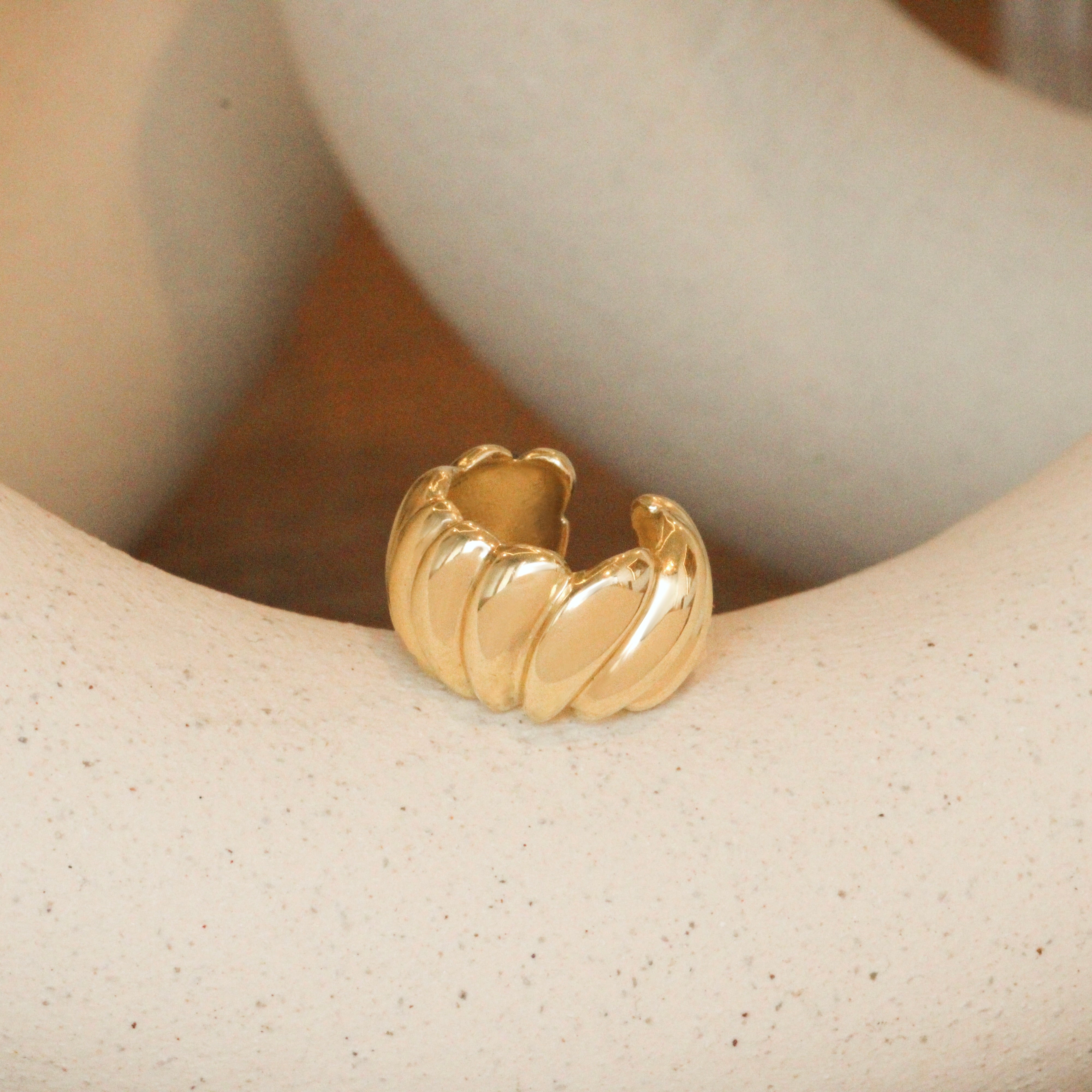 Lifestyle angled view of Venus Ear Cuff by Mon Pilar on a ceramic with blurred background