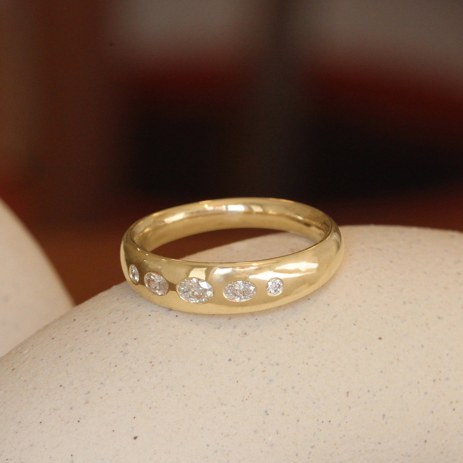 Lifestyle angled view of Ellipse Band 5mm / Flush Oval Lab Diamond in 14k Yellow Gold by Goldpoint Jewelry on a ceramic