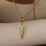 Lifestyle view of Engraved Pesca Sand Charm / Round Natural Diamond by Erin Cuff hanging over a ceramic with a blurred natural hued background