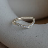 Lifestyle side profile view of Flat Band 2mm Deep Curve / Pave Round Diamonds / in 14k White Gold by Goldpoint Jewelry on a ceramic with blurred background