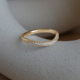 Lifestyle angled side view of Flat Band 2mm Soft Curve / Pave Round Diamonds / in 14k Yellow Gold by Goldpoint Jewelry on a ceramic with a blurred background