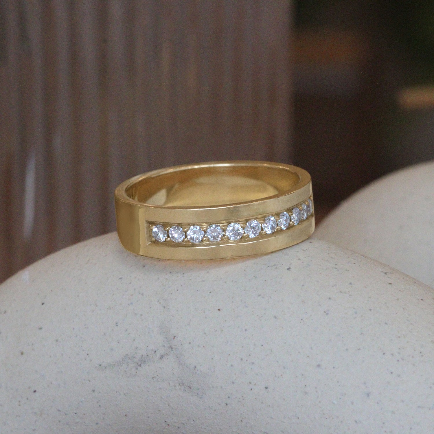 Lifestyle angled view of Flat Band 6mm / Bright Cut Lab Diamonds in 14k yellow gold by Goldpoint Jewelry on a ceramic with a blurred background