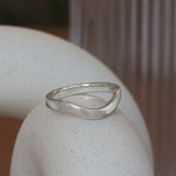 Lifestyle angled side view of Flat Wide Band Deep Curve in Platinum by Goldpoint Jewelry on a ceramic with blurred background