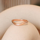 Lifestyle angled view of Flat Band 2mm Deep Curve / in 14k Rose Gold by Goldpoint Jewelry on a ceramic with blurred background