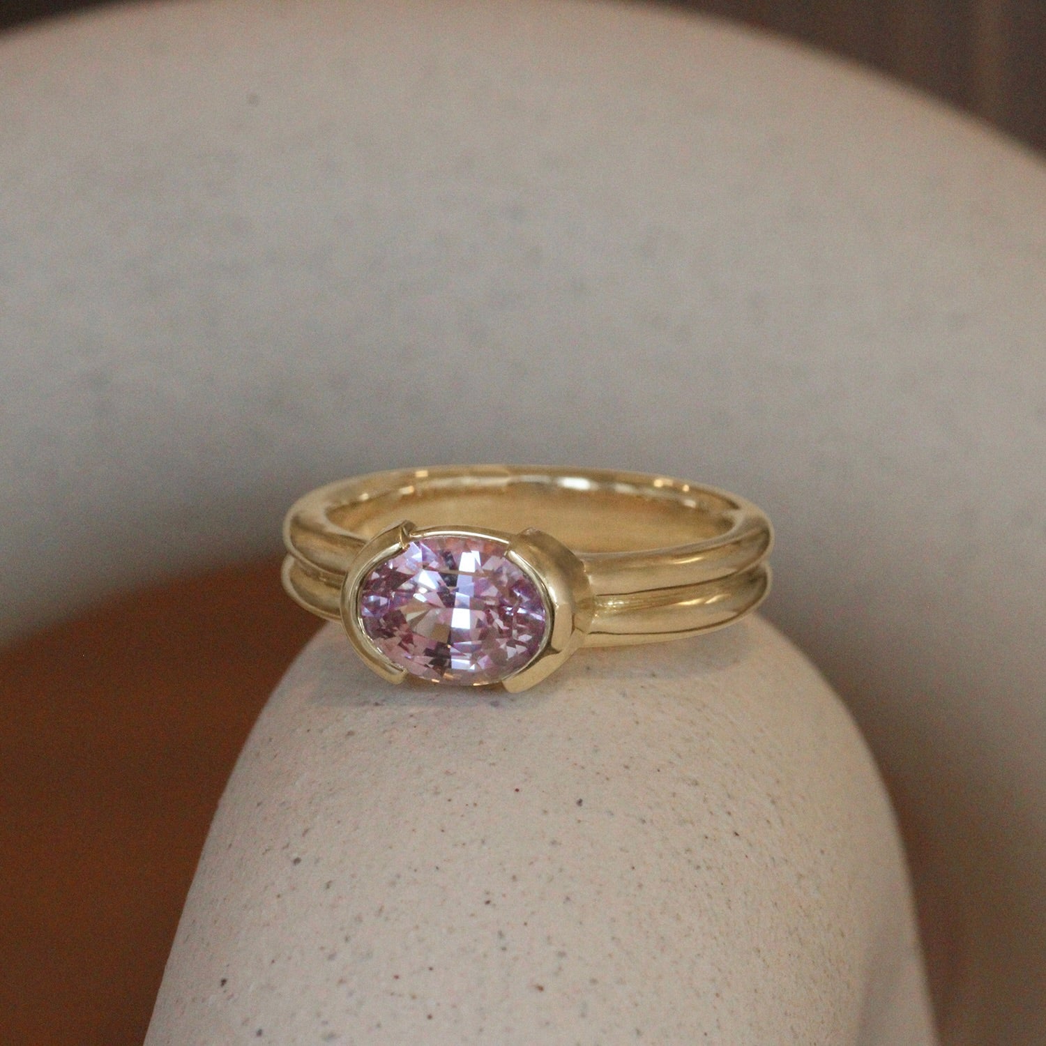 Lifestyle view of Franklin Ring Oval Sapphire 2.11ct by Goldpoint Jewelry on a ceramic with a blurred background