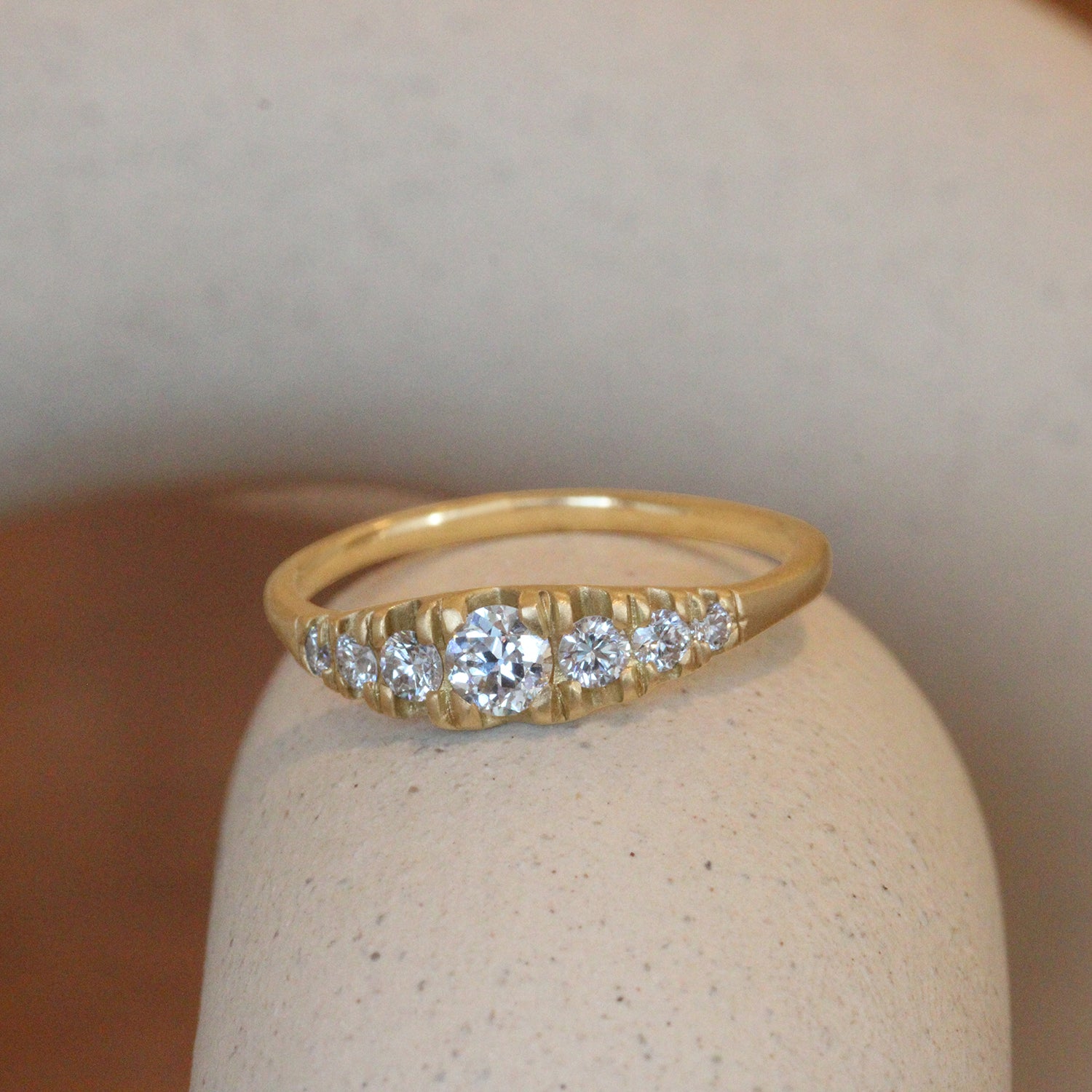 Lifestyle angled view of Grand Pave Diamond Rubidoux Ring / Round Natural Diamond 0.20ct by Erin Cuff on a ceramic with a blurred background