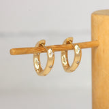Lifestyle angled view of Hilma Hoops / Natural Round Diamonds by 12th House on a wooden stand with blurred background