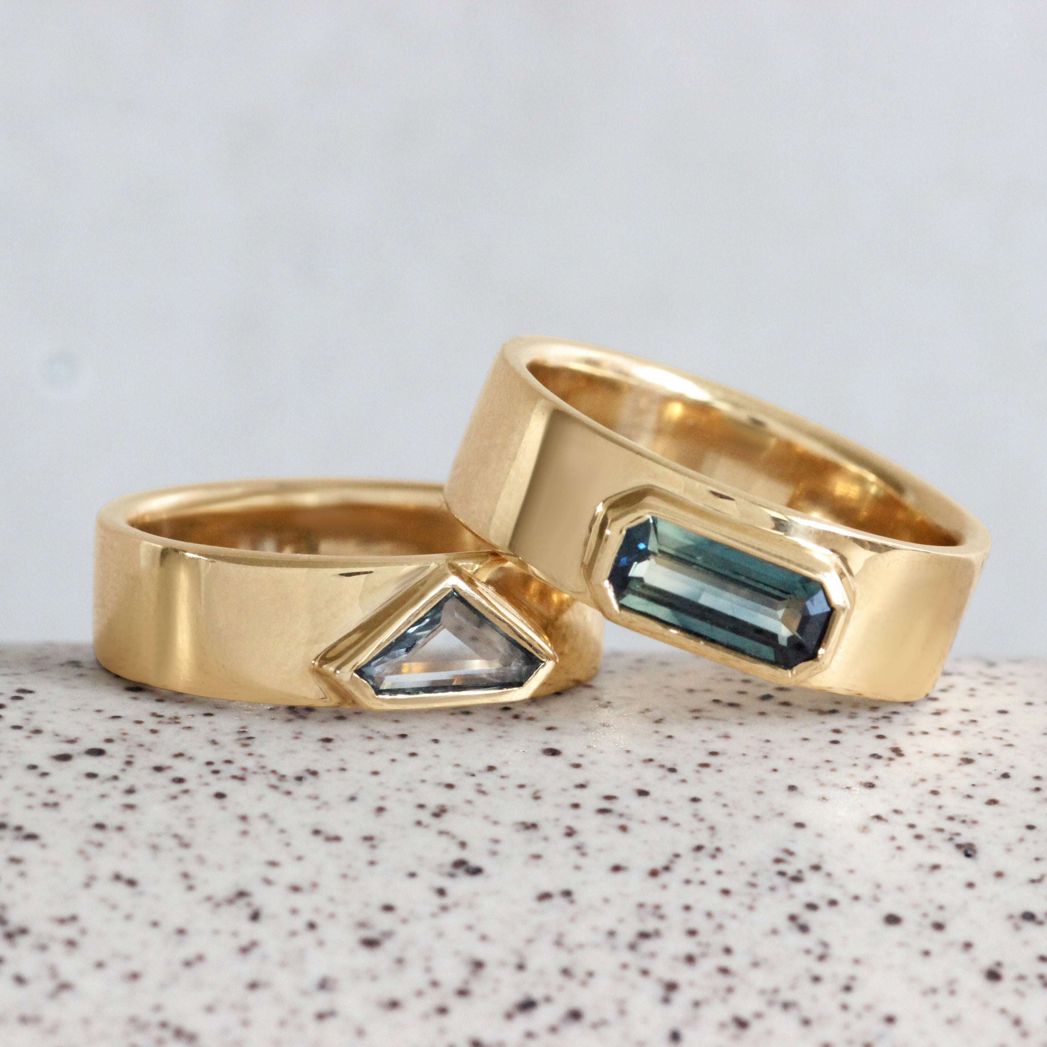 Lifestyle stacked view of Kingsland Ring Emerald Cut Sapphire 1.2ct in 14k yellow gold stacked on another ring by Goldpoint Jewelry on a ceramic