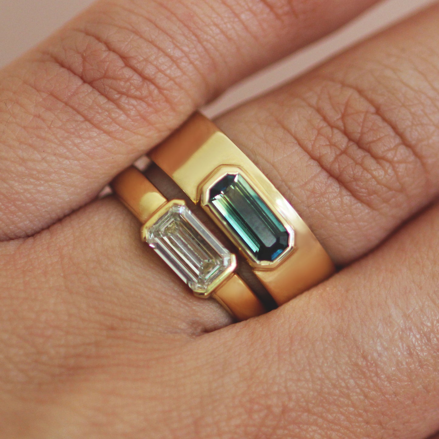 Model wearing Horizon Band / Bicolor Blue Yellow Emerald Cut Sapphire stacked on an engagement ring