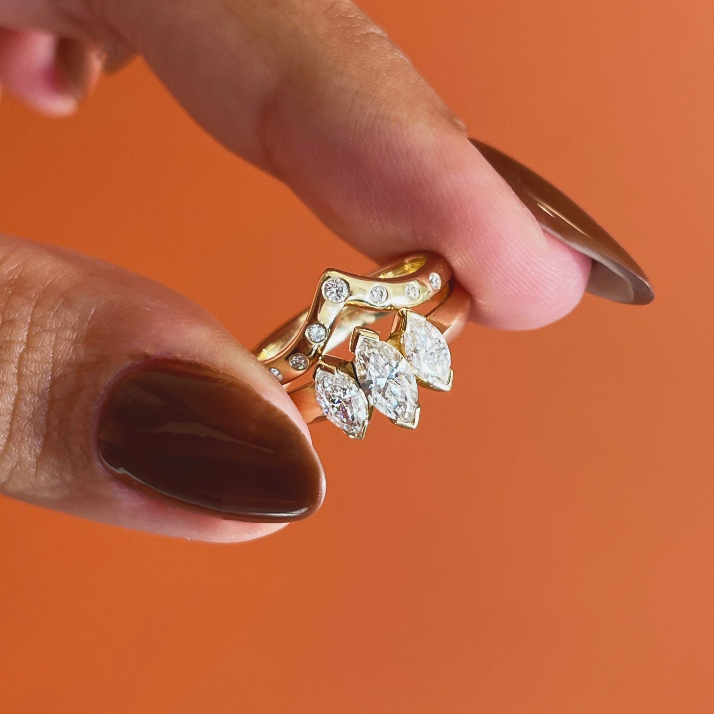 Model holds Peak Dome Band Flush Round Lab Diamonds in 14k yellow gold with an engagement ring by Goldpoint