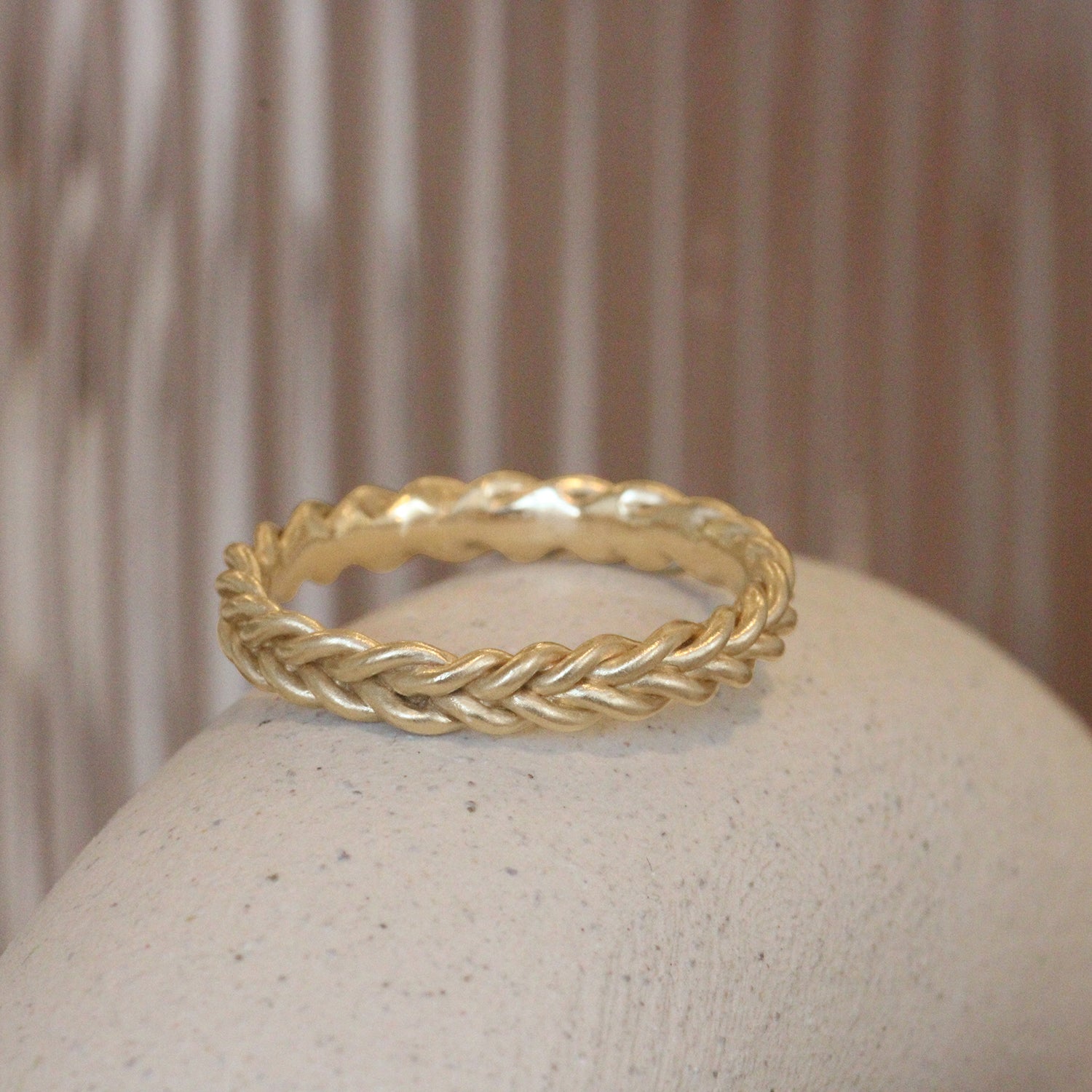 Lifestyle angled view of Kismet Band in 14k yellow gold by Leili Kasraie on a ceramic with a blurred background