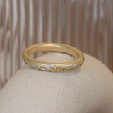 Lifestyle angled side view of Micro Celestial Band /  Pave Round Natural Diamond by Pieces of Starr on a ceramic with blurred background