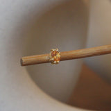 Lifestyle angled view of Miro Earring / Oval Orange Spessartite Garnet in 14k yellow gold by Goldpoint Jewelry on a wooden stand with a blurred background
