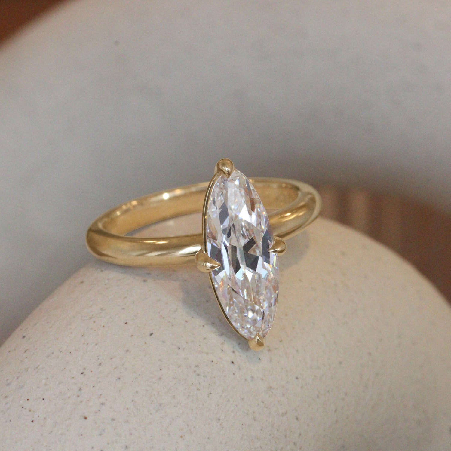 Lifestyle angled view of Noble Ring Moval Lab Diamond 2.24ct by Goldpoint Jewelry sitting on a ceramic with a blurred background