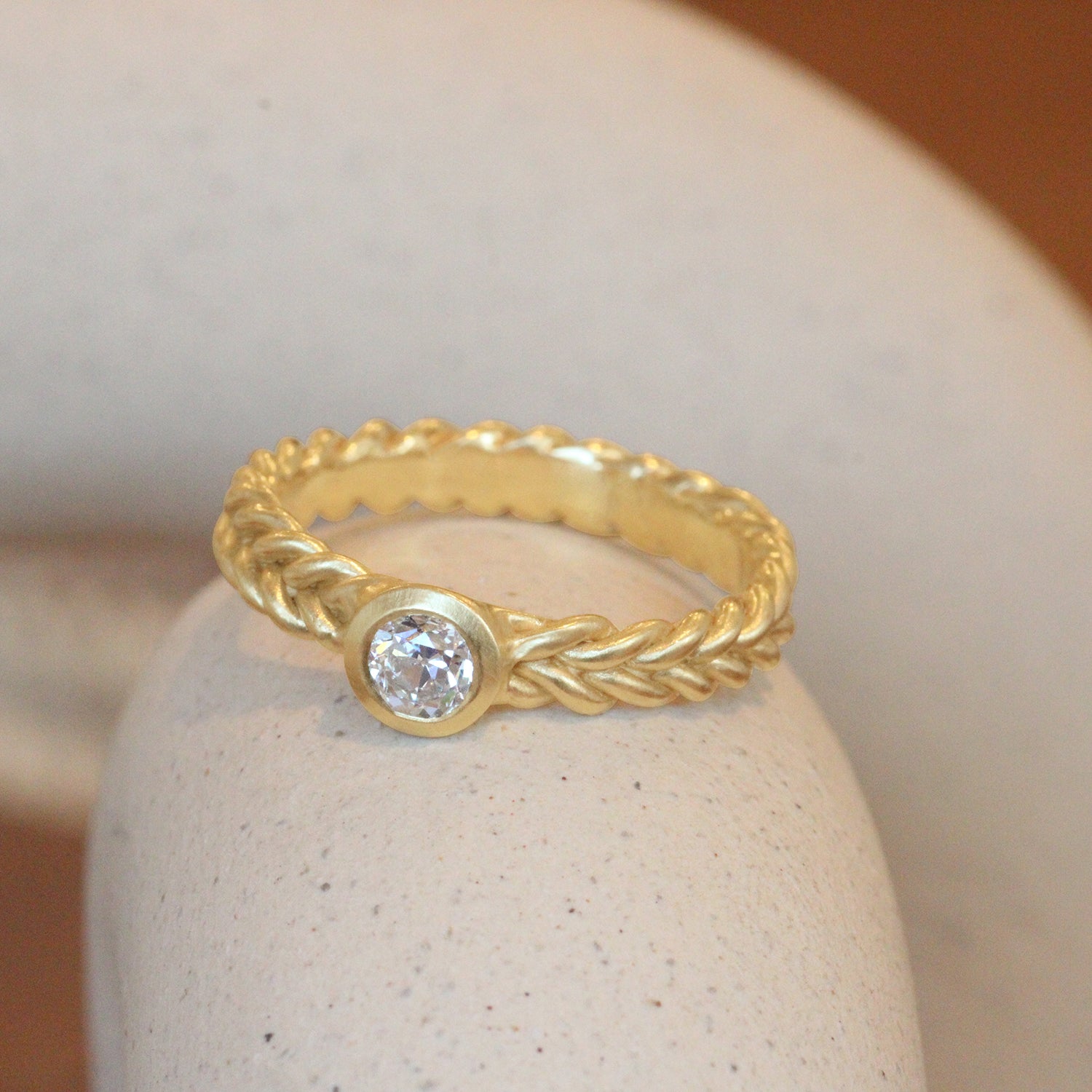 Lifestyle angled side view of Old Euro Kisment Band by Leili Kasraie Studio on a ceramic with a blurred background