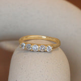 Lifestyle angled view of Petite Grove Ring in 18k yellow gold by Erin Cuff on a ceramic with a blurred background