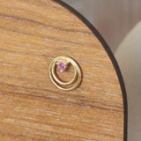Lifestyle angled side view of Ripple Earring / Round Ruby in 14k yellow gold by Goldpoint Jewelry on a wooden display