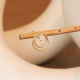 Lifestyle angled view of Ripple Earring / Lab Round Diamond by Goldpoint Jewelry on a wooden stand with blurred background