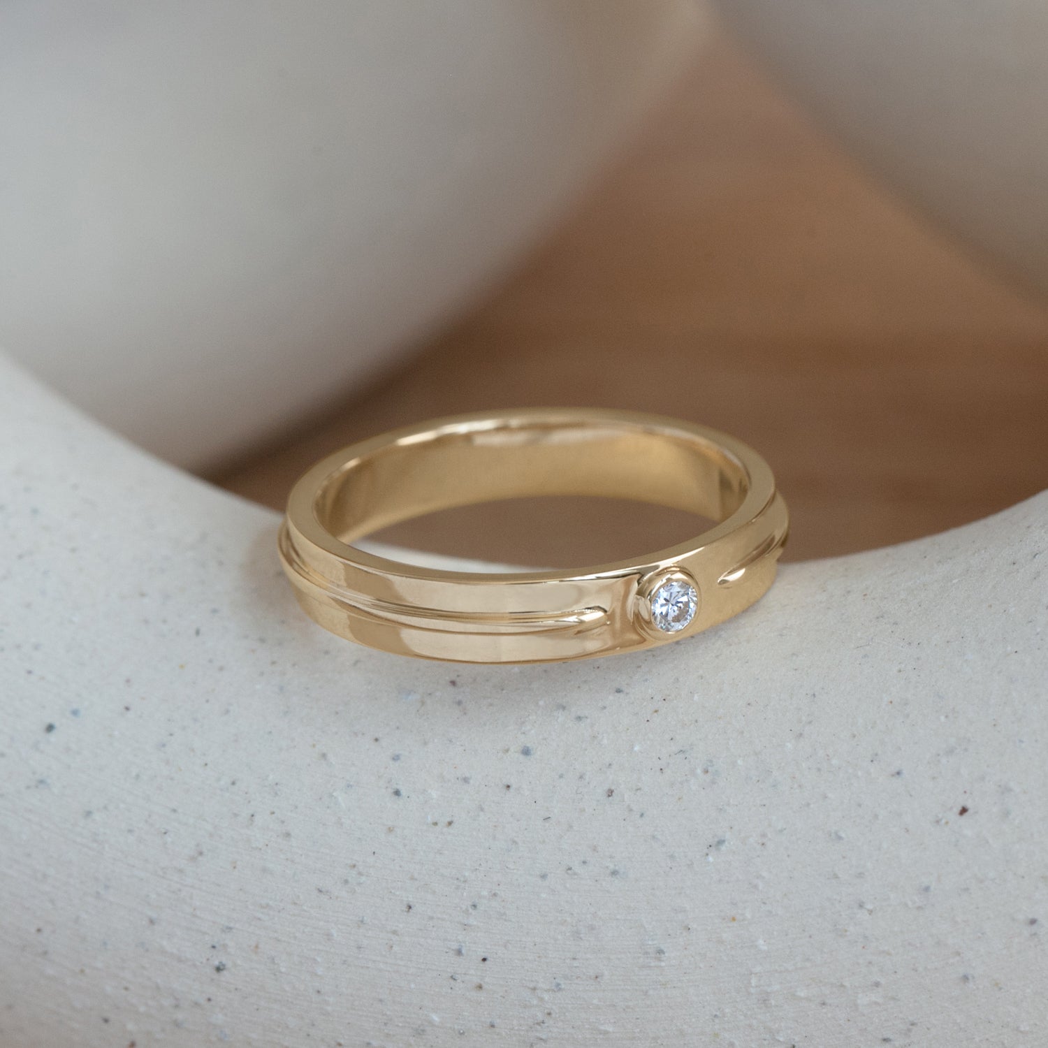 Lifestyle side angled view of Atmosphere Band / Round Natural Diamond 0.10ct by Sandy Rubin on a ceramic with a blurred taupe background