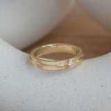 Lifestyle side angled view of Atmosphere Band / Round Natural Diamond 0.10ct by Sandy Rubin on a ceramic with a blurred taupe background